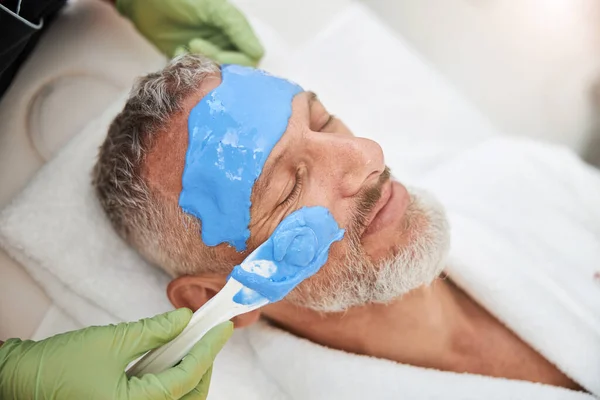 Contented elderly man having a facial mask for his skin — Stock Photo, Image
