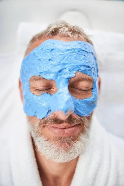 Senior citizen having a moisturizing facial mask — Stock Photo, Image
