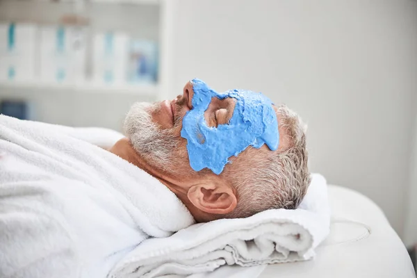 Relaxed elderly man is receiving beautification procedures — Stock Photo, Image