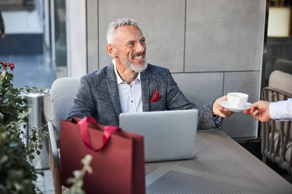 Un jubiloso anciano con un portátil tomando una taza de té — Foto de Stock