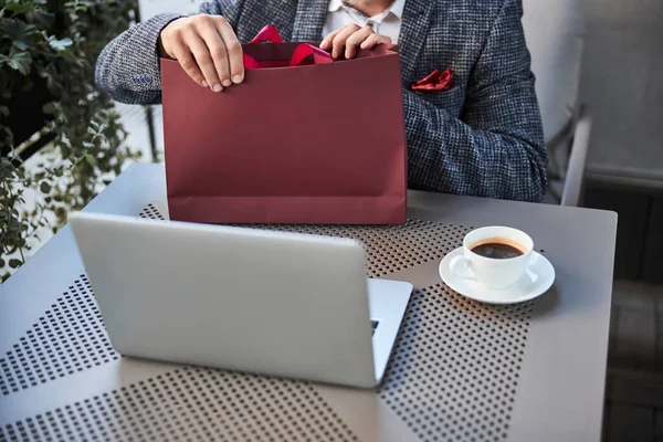 Elegante hombre desempacando una bolsa en una mesa de café — Foto de Stock