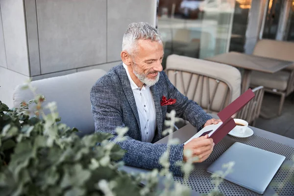 Smiley senior man looking at card inside a box — Stock Photo, Image