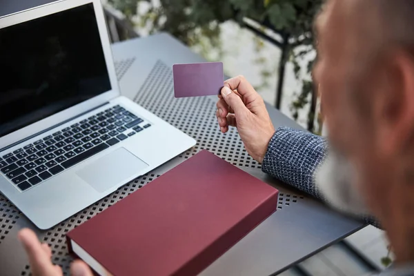 Affärsman med ett plastkort i handen sitter med bärbar dator — Stockfoto