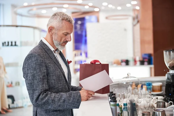 Geconcentreerde oudere man op zoek naar de bar menu — Stockfoto