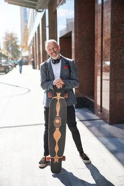 Mooie oudere man die op straat staat met een longboard — Stockfoto