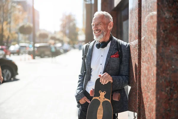 Positiv äldre gentleman poserar med en longboard — Stockfoto