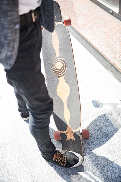 Stylish man stepping on a cool longboard — Stock Photo, Image