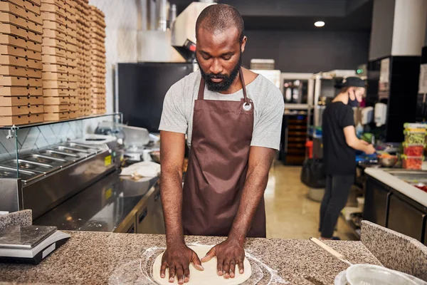 Jonge man met baard die pizza maakt in de keuken — Stockfoto