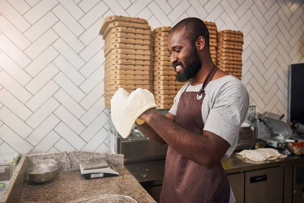 Jolly ung man njuter av att göra pizza i caféet — Stockfoto