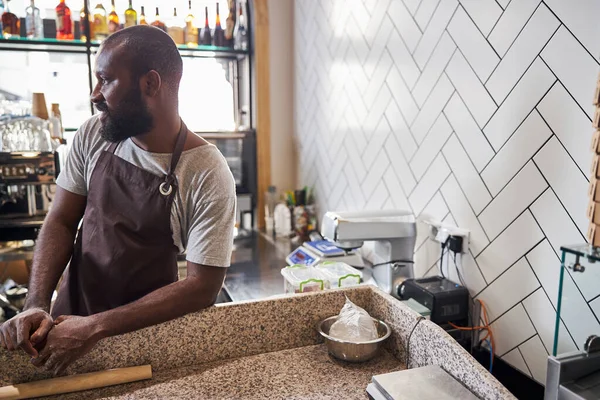 Vrolijke jongeman ontspannen na het maken van deeg in cafe — Stockfoto