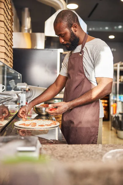 Fröhlich gutaussehender Koch macht Pizza im Café — Stockfoto