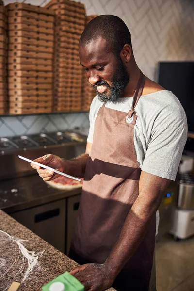 Vrolijke jonge chef met touchpad op het werk — Stockfoto