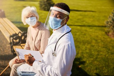 Heyecanlı doktor ve emekli kameraya bakıyor.