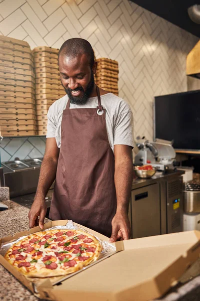 Beau Afro-Américain debout au comptoir avec une pizza — Photo