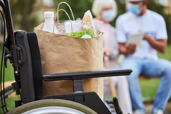 Paper bag with grocery purchases on the wheelchair — Stock Photo, Image