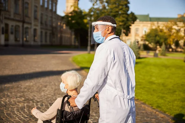 Ärztin schiebt Rollstuhl mit Seniorin — Stockfoto