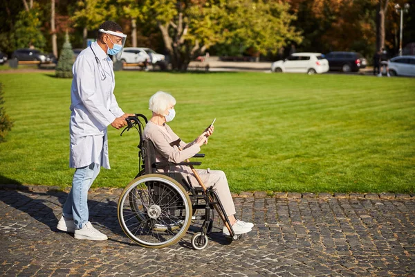 Az orvos és a fogyatékos betege a szabadban töltik az idejüket. — Stock Fotó