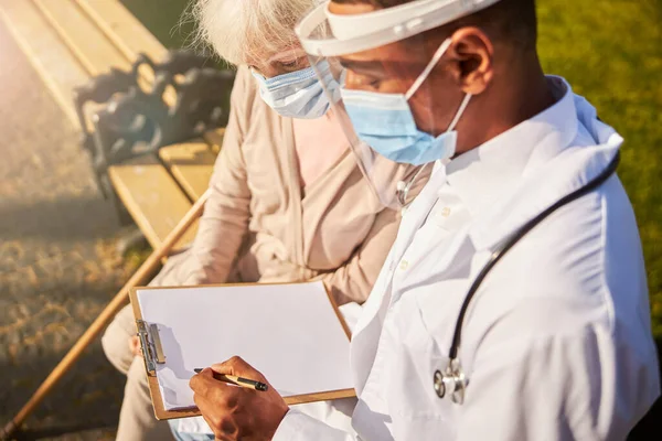 Médico geral escrevendo em uma página em branco — Fotografia de Stock