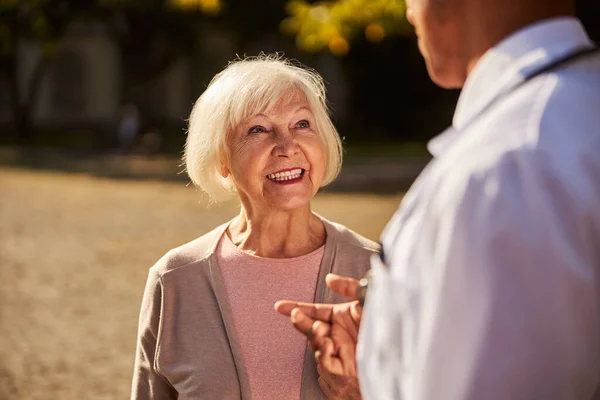 Удовлетворенная стареющая женщина, улыбающаяся доктору — стоковое фото