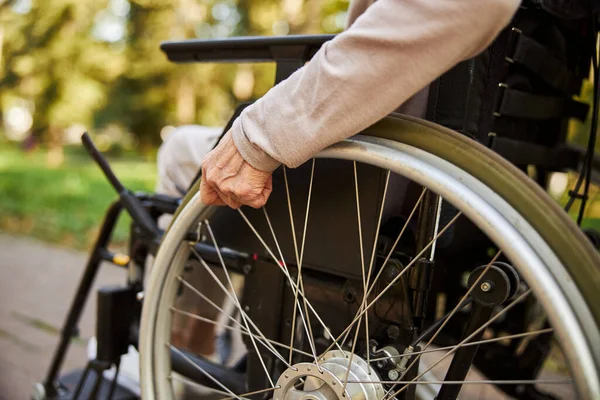 Adulto sênior está girando a roda da cadeira de rodas — Fotografia de Stock