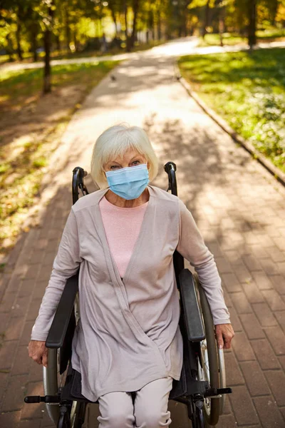 Behinderte Frau im Rollstuhl auf einer Parkstraße — Stockfoto