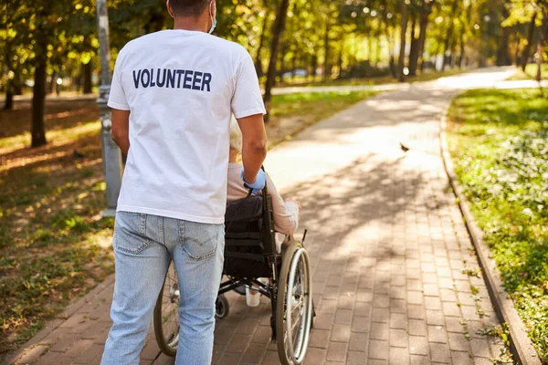 車椅子で老人を転がすボランティア — ストック写真