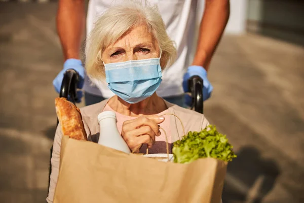 Trauriger Rentner hält Päckchen mit Lebensmitteln in der Hand — Stockfoto