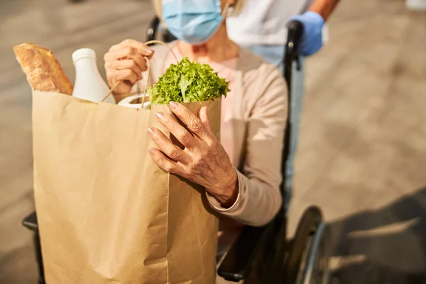 Mujer jubilada transportando una bolsa de papel de tienda de comestibles con comida —  Fotos de Stock