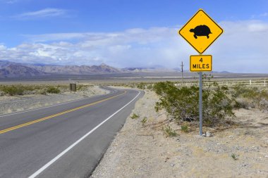 Desert Tortoise crossing warning road sign with mountain backdrop clipart