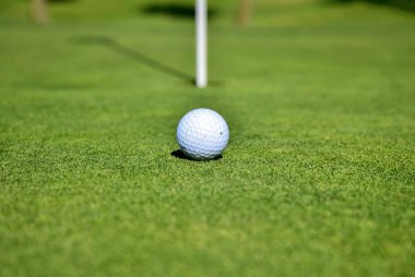 White golf ball and pin flag stick on putting green clipart