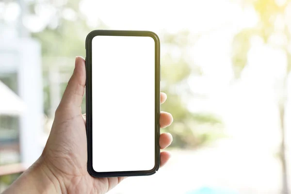 Mockup of blank screen mobile phone. Man hand holding and using a mobile phone with white blank screen against bokeh of nature background.
