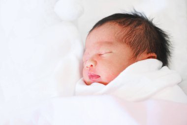 Yeni doğmuş bebek beyaz battaniyeyle uyuyor..