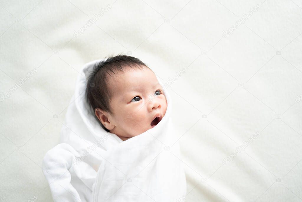 Newborn baby in white blanket.