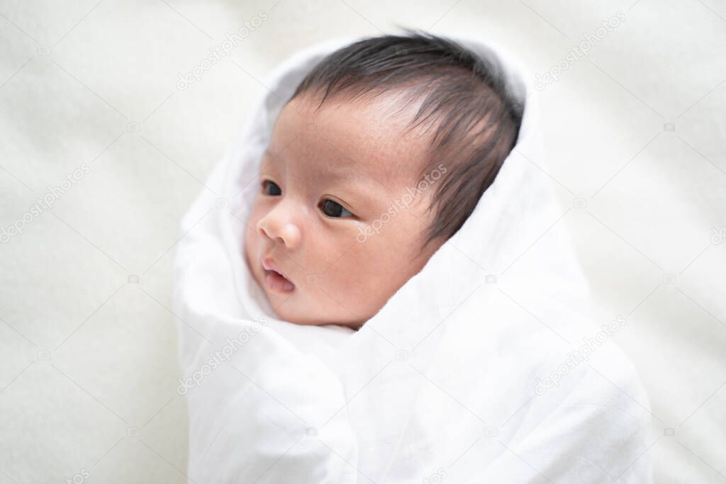 Newborn baby in white blanket.