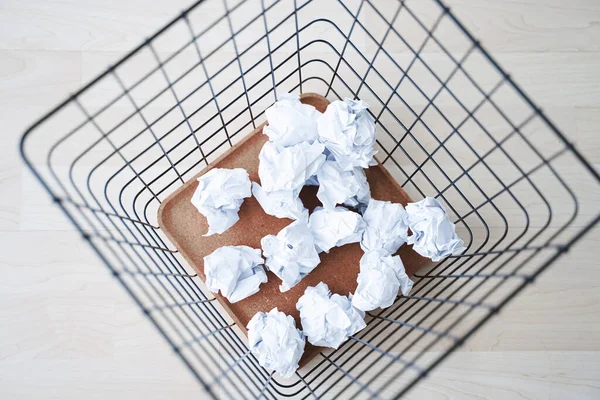 Trash basket and paper crumples. Overflowing waste paper in office garbage bin.