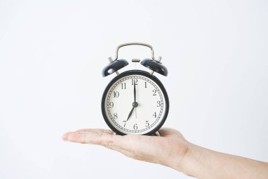 Beyaz arkaplanda el ele tutuşan alarm saati.