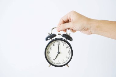 Beyaz arkaplanda el ele tutuşan alarm saati.