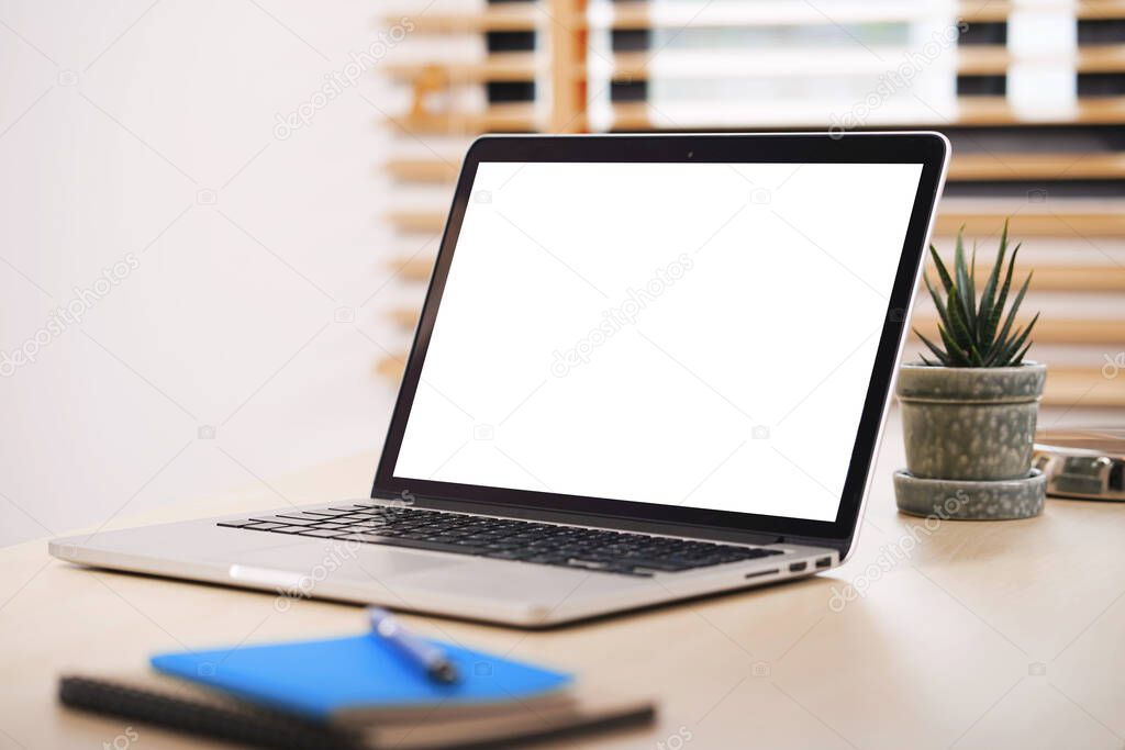 Conceptual workspace, Laptop computer with blank white screen on table.                 
