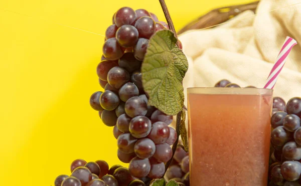 Red grape juice (Vitis vinifera). Yellow background. Bunches of pink grape. Table fruits. Energy and natural drink. Fruit consumed fresh, in the preparation of juices, sweets, jams and table wines.