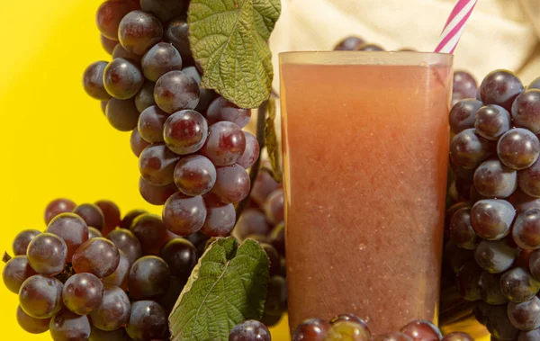 Red grape juice (Vitis vinifera). Yellow background. Bunches of pink grape. Table fruits. Energy and natural drink. Fruit consumed fresh, in the preparation of juices, sweets, jams and table wines.