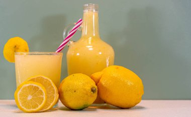 Limonata içeceğim. Limonata, yemeklere eşlik eden ya da lezzetli bir atıştırmalık besteleyen ferahlatıcı bir içecektir. Limon suyu. Yeşil arkaplan.