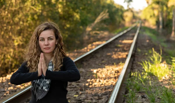 Brazilian woman. Young blond girl meditating. Beautiful young woman practicing Buddhism. Train tracks. Woman meditating on the rails. Brazilian blonde with curly hair practicing yoga.