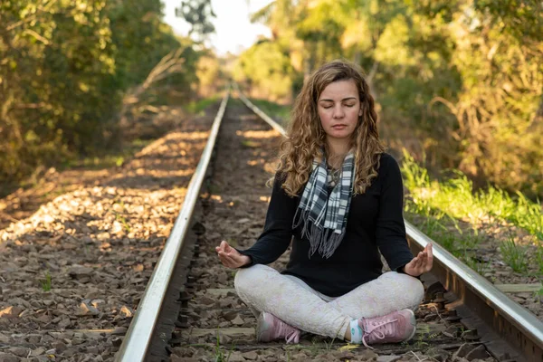 ブラジル人女性 若い金髪の女の子が瞑想 美しい若い女性は仏教を実践する 列車の線路 女はレールの上で瞑想 ブラジルのブロンドとともに巻き毛練習ヨガ — ストック写真