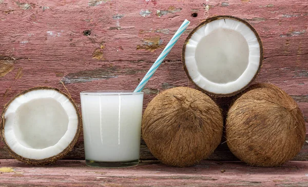 Glass of fresh coconut milk. Fruit cut in half and fresh. Coconut milk is extracted from the pulp of the coconut fruit, one of the main vegetable resources of humanity and very rich in nutrients.