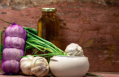 Bir bardak zeytinyağı. İşlenmiş soğanlar ve taze sarımsak. Baharat için yeşil sarımsak yaprakları. Soda. Mutfak lezzeti. Ahşap arka. Brezilya mutfağı..