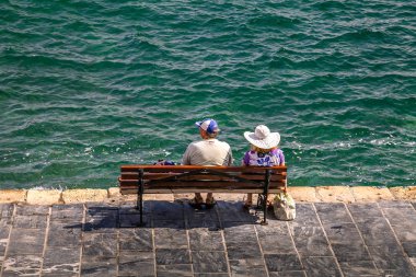 Eski limanda bankta turistler. Yunanistan. Girit. Hanya. 