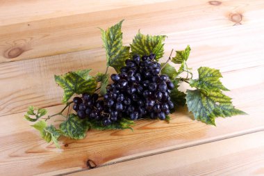 Siyah üzüm ve yapraklar masada.