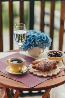 Balkonda sabah kahvaltısı, kruvasan, kahve ve böğürtlen.