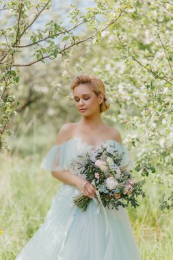 Baharın çiçek açan bahçesinde gelinlik giymiş güzel bir gelin.