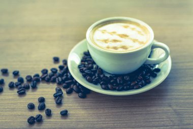 Sıcak kahve ile sanat desen ahşap masa arka plan üzerinde beyaz Kupası 